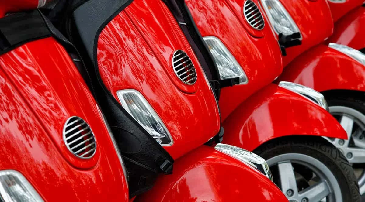 A row of red mopeds parked side by side