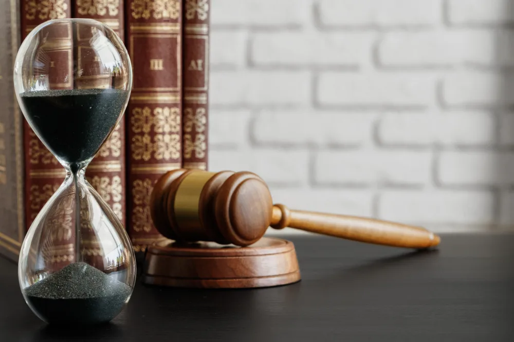 Hourglass beside a judge's gavel and law books
